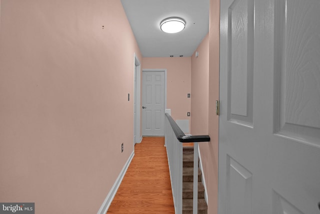 hallway with an upstairs landing, light wood-style flooring, and baseboards