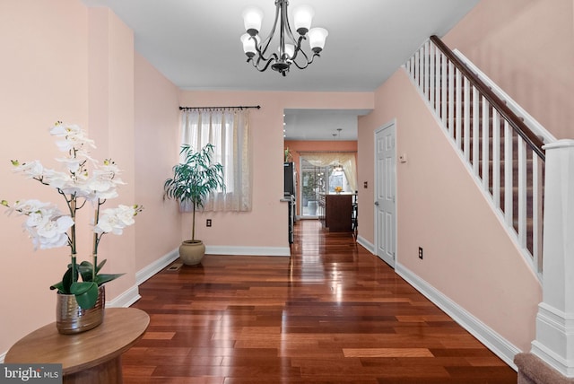 entryway featuring dark wood-style floors, stairs, baseboards, and an inviting chandelier