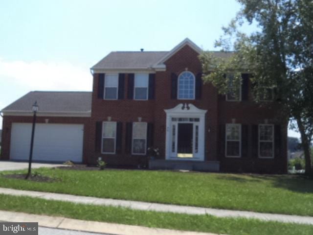 colonial-style house with an attached garage, driveway, and a front lawn