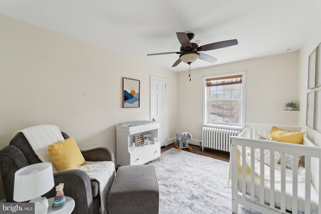 bedroom with a ceiling fan, radiator heating unit, and wood finished floors