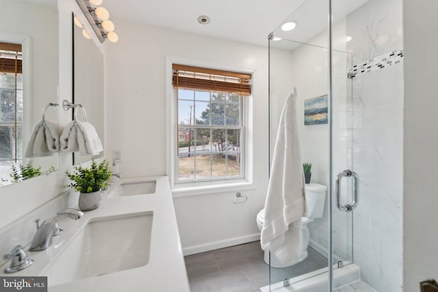 bathroom with baseboards, double vanity, a sink, and a shower stall