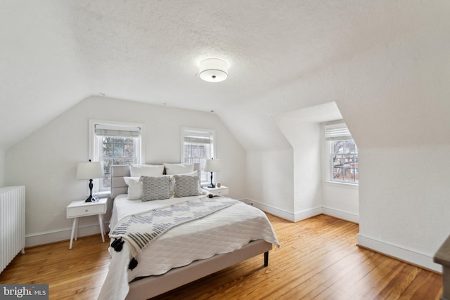 bedroom featuring multiple windows, hardwood / wood-style floors, and radiator heating unit