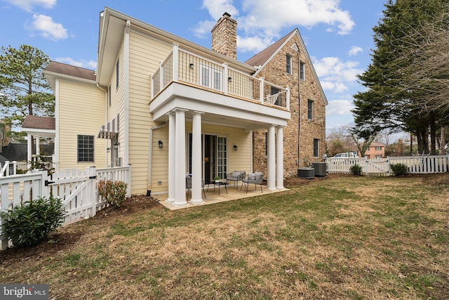 rear view of house featuring a gate, a patio area, a lawn, and a fenced backyard