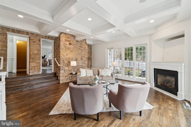 living room with coffered ceiling, wood-type flooring, a glass covered fireplace, and beam ceiling