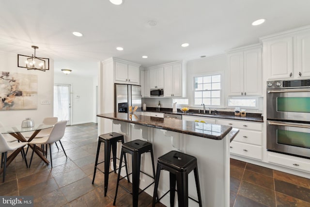 kitchen with a wealth of natural light, appliances with stainless steel finishes, stone tile flooring, and white cabinets