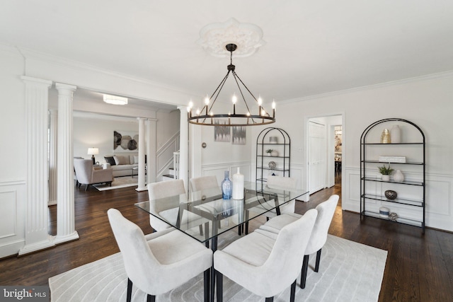 dining area with wood finished floors, stairway, wainscoting, ornate columns, and crown molding