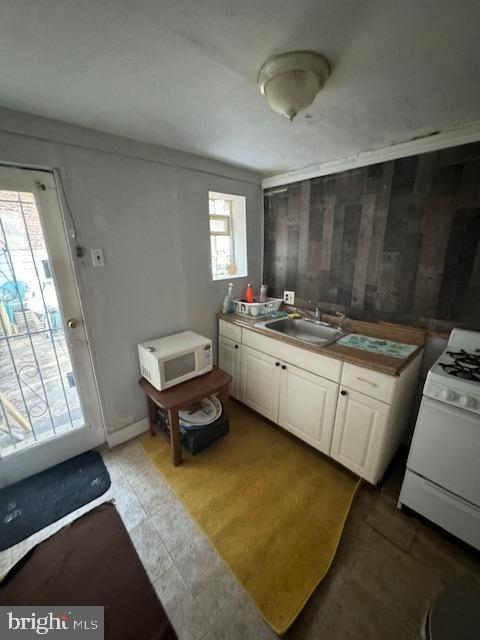 kitchen with white appliances, white cabinets, and a sink