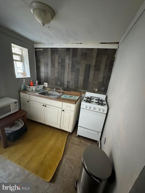 kitchen with white appliances, a sink, and white cabinets