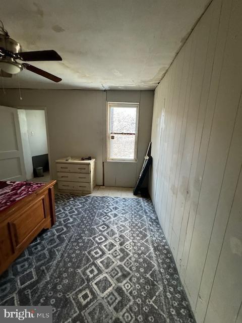 bedroom with wood walls and a ceiling fan