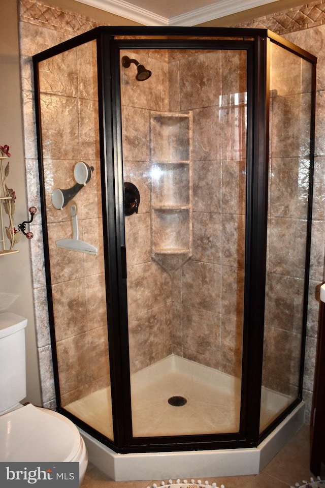 bathroom featuring toilet, a shower stall, and ornamental molding