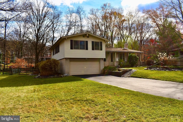 tri-level home with driveway, a chimney, fence, a front lawn, and brick siding