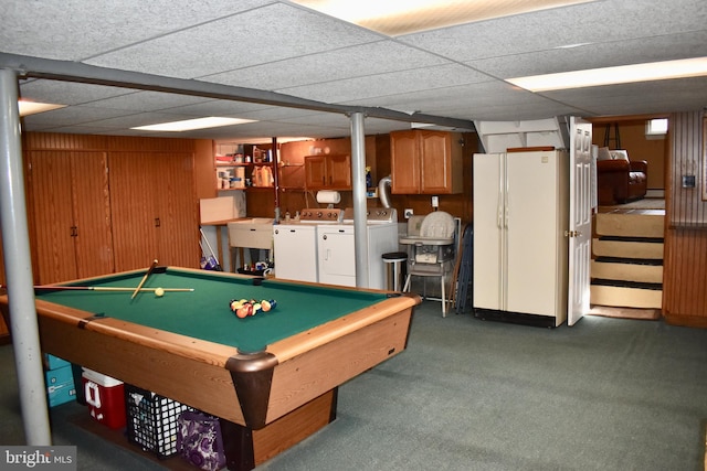 playroom with a paneled ceiling, wood walls, a sink, washer and clothes dryer, and dark carpet