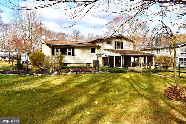 rear view of property with a sunroom, a lawn, a chimney, and fence