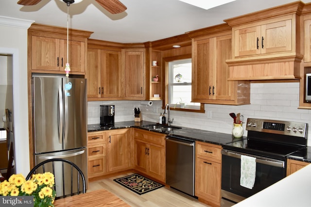 kitchen with decorative backsplash, ceiling fan, light wood-style flooring, stainless steel appliances, and a sink