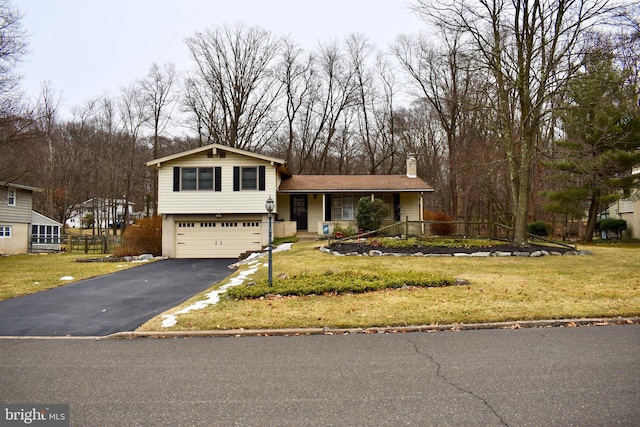 split level home featuring driveway, a garage, a chimney, and a front lawn