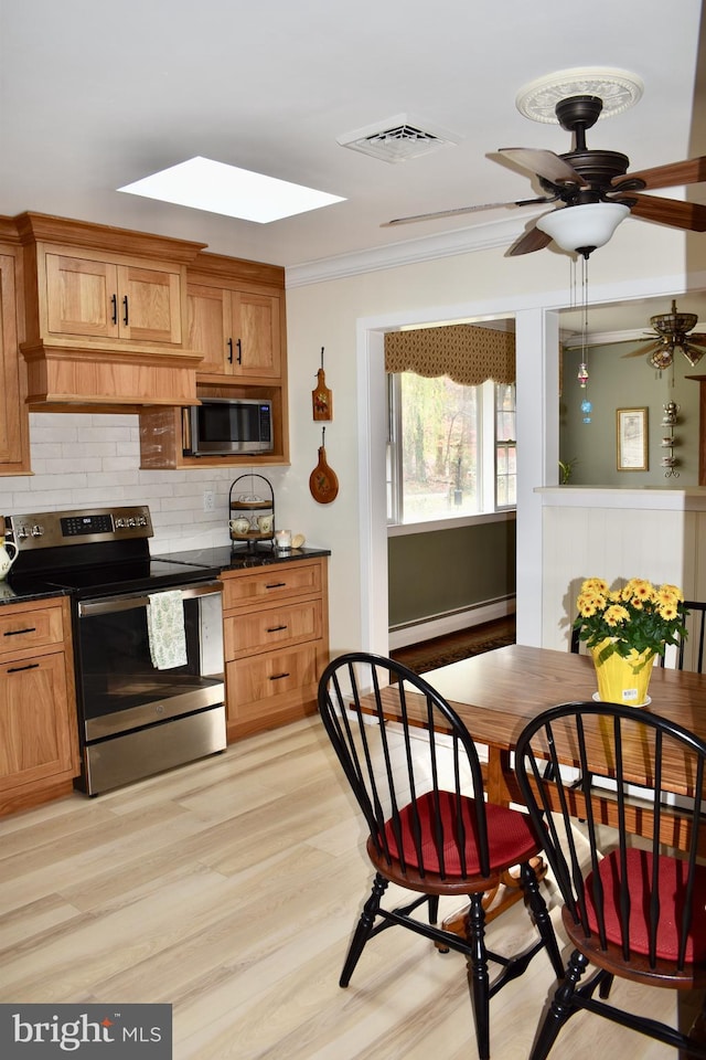 kitchen with appliances with stainless steel finishes, dark countertops, a baseboard heating unit, and visible vents