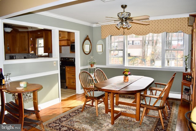 dining area featuring a ceiling fan, ornamental molding, and wood finished floors