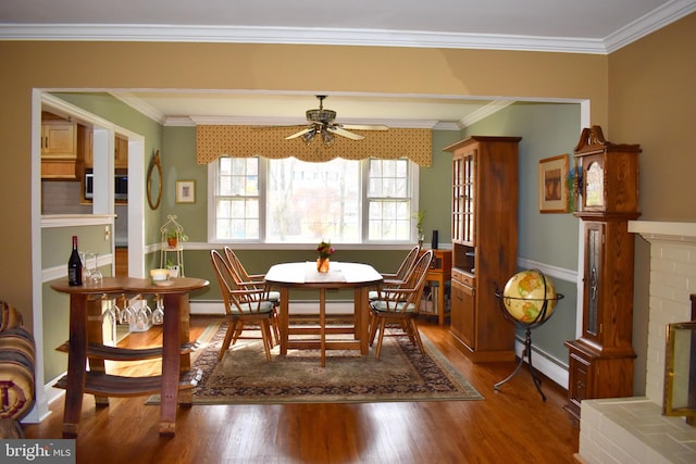 dining room with crown molding, a fireplace, a baseboard heating unit, and wood finished floors