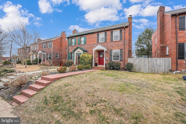 view of front of house featuring brick siding, a front yard, and fence