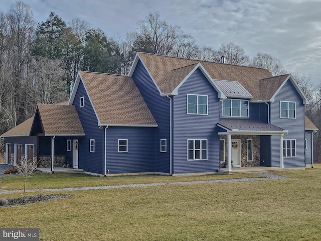 view of front facade featuring roof with shingles, an attached garage, a standing seam roof, a patio area, and a front yard