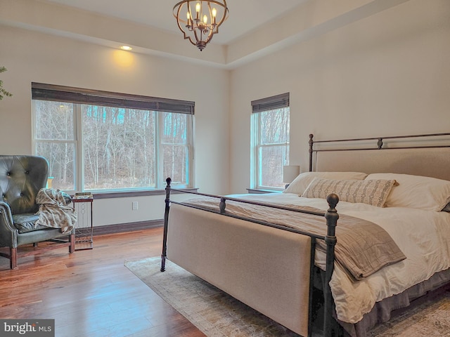 bedroom with an inviting chandelier and wood finished floors