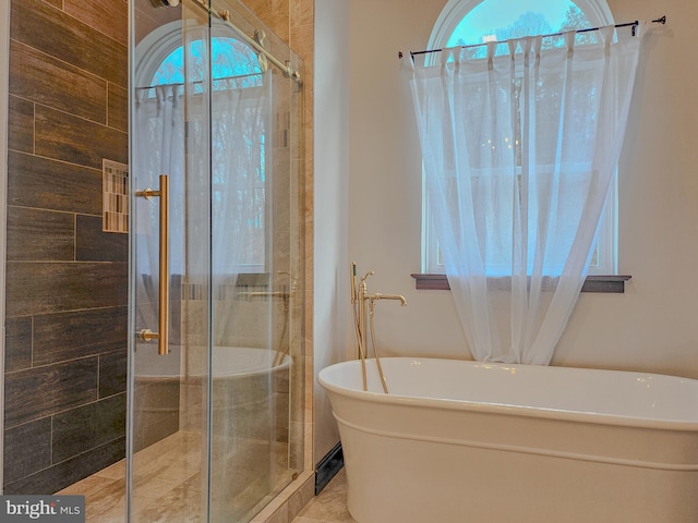 full bath with a soaking tub, plenty of natural light, and a tile shower