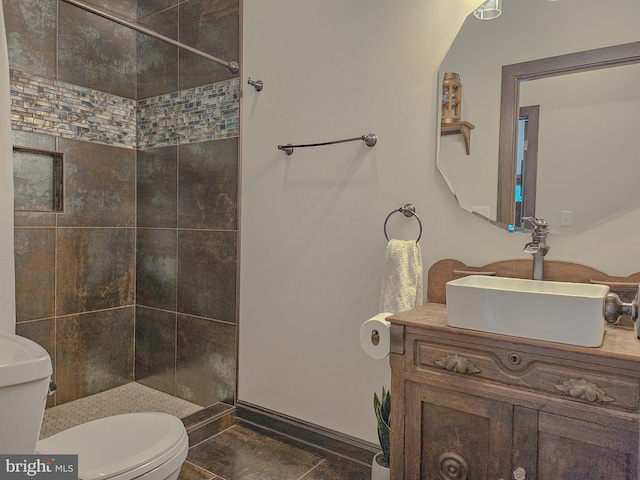 bathroom with vanity, a shower stall, toilet, and baseboards