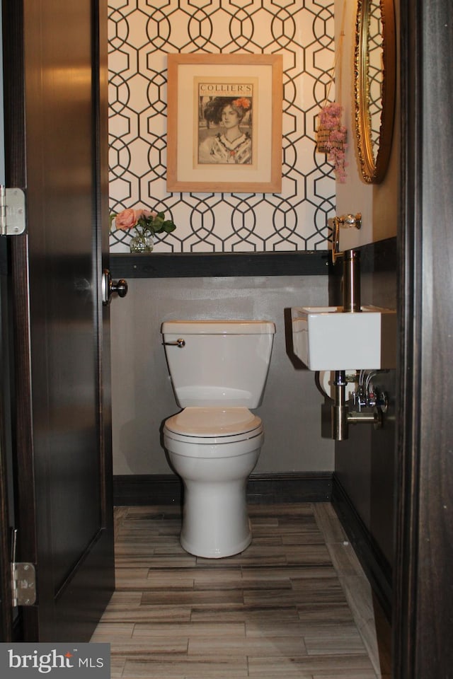 bathroom with wood finished floors, a sink, toilet, and baseboards