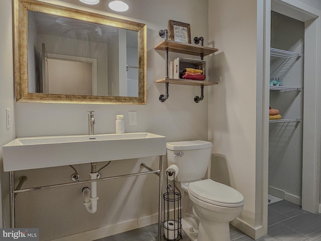 bathroom featuring toilet, baseboards, and a sink