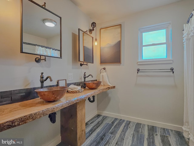 bathroom featuring double sink, baseboards, and wood finished floors