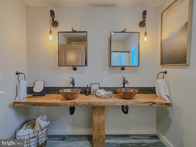 full bath with baseboards, wood finished floors, and dual sinks