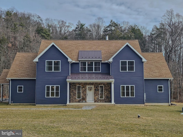 view of front of house featuring a front yard, stone siding, and roof with shingles