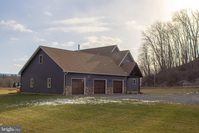 view of side of property with roof with shingles, a yard, a garage, stone siding, and driveway