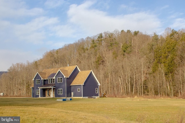 view of front facade with a front lawn and a view of trees