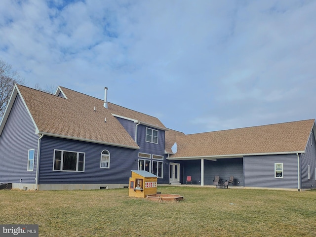 rear view of house featuring a yard, a patio, and roof with shingles