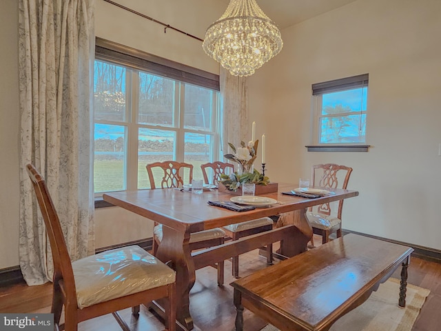 dining space with wood finished floors and a notable chandelier