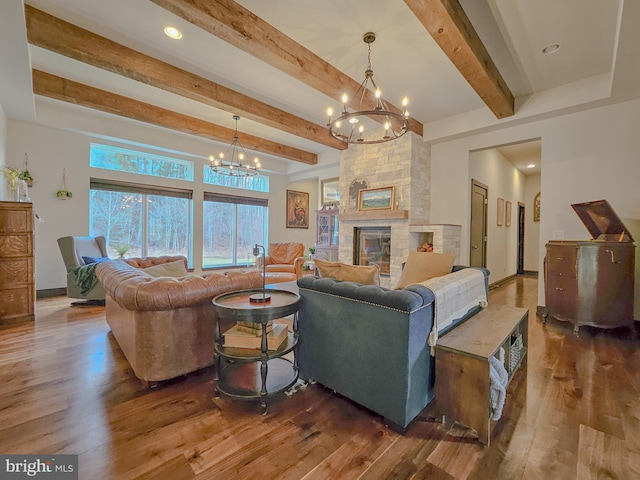 living area featuring baseboards, dark wood finished floors, beamed ceiling, a fireplace, and a chandelier