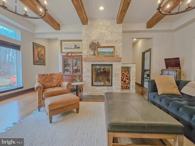 living area featuring baseboards, a fireplace, light wood-style flooring, and beamed ceiling