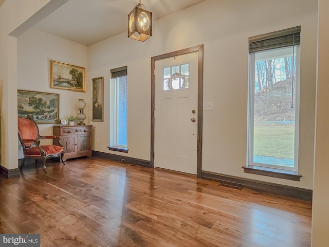 foyer with a chandelier, visible vents, baseboards, and wood finished floors