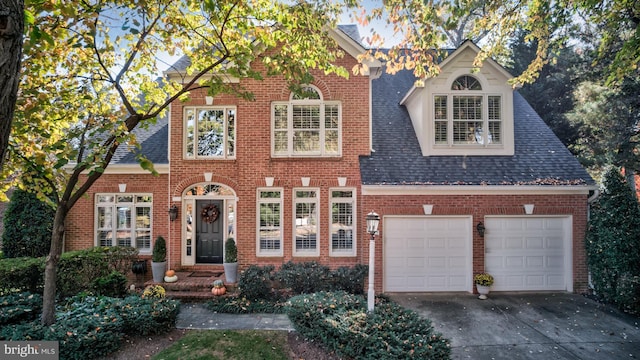 traditional home with driveway, a shingled roof, and brick siding