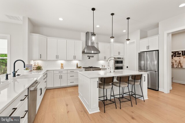5817 2nd St S, Arlington, VA 22204 - kitchen with stainless steel appliances, wall chimney exhaust hood, a sink, backsplash, and light wood-type flooring