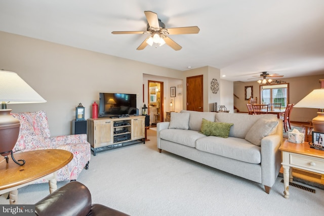 living room featuring light carpet, visible vents, and a ceiling fan