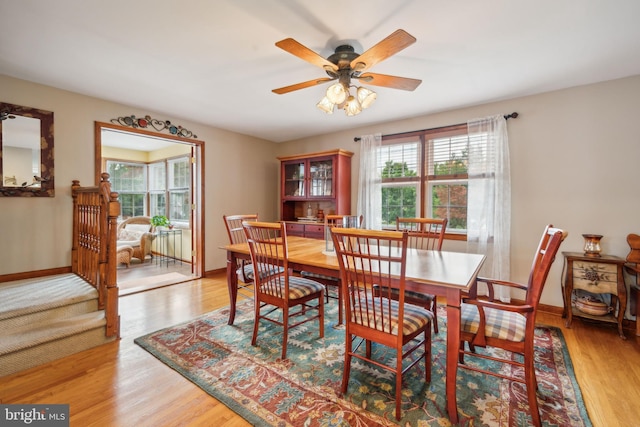 dining space with baseboards, a healthy amount of sunlight, a ceiling fan, and light wood-style floors