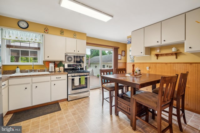 kitchen with gas stove, a sink, and white cabinetry