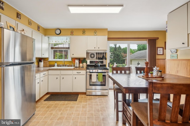 kitchen featuring white cabinets, appliances with stainless steel finishes, light countertops, a healthy amount of sunlight, and a sink