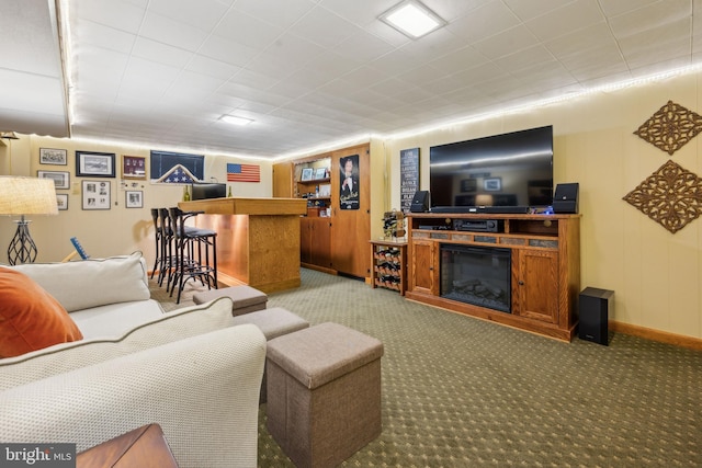 living area featuring light carpet, baseboards, a dry bar, and a glass covered fireplace