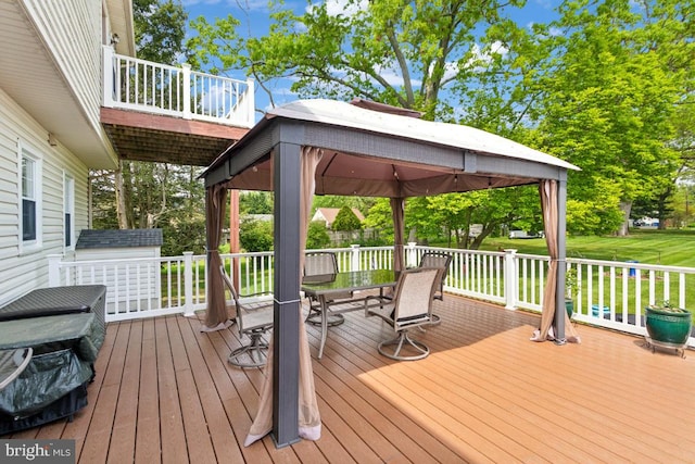 wooden deck featuring a yard, outdoor dining area, and a gazebo