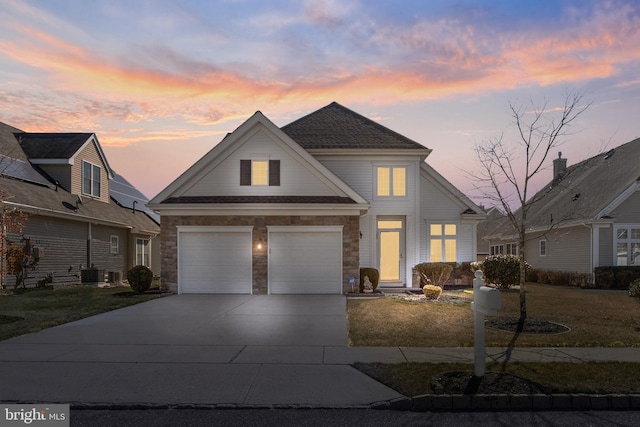 traditional home with a garage, concrete driveway, a front lawn, and stone siding