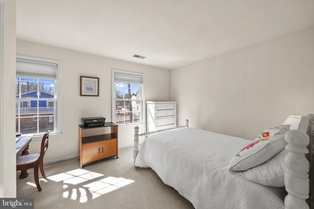 carpeted bedroom with visible vents and multiple windows