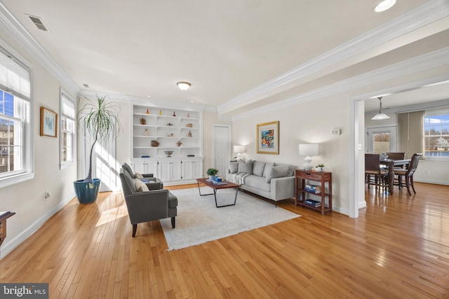 living room with baseboards, visible vents, built in features, ornamental molding, and light wood-type flooring